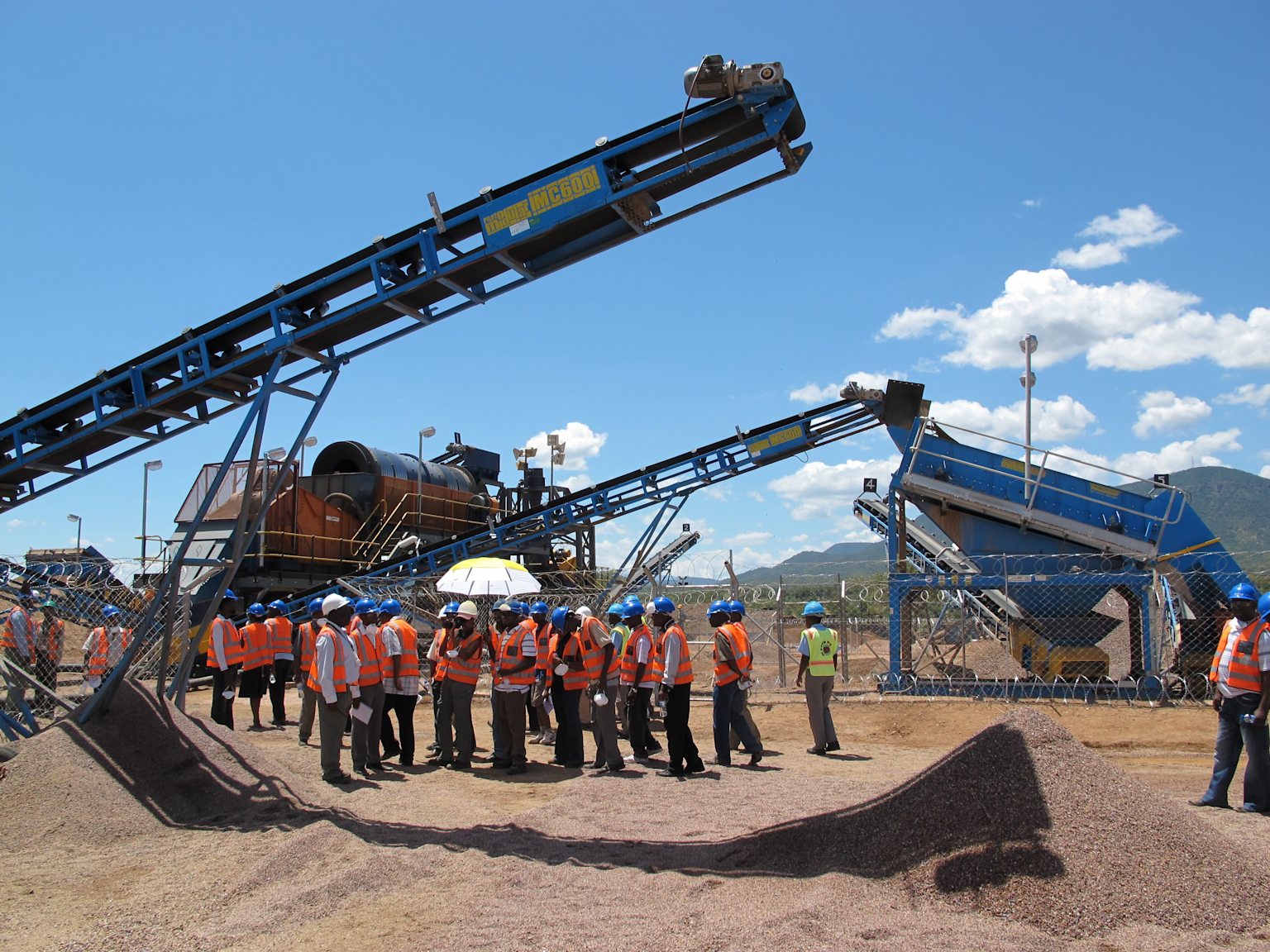 Workers and security personnel at the Marange diamond mine in Zimbabwe amid active mining operations and conveyor equipment